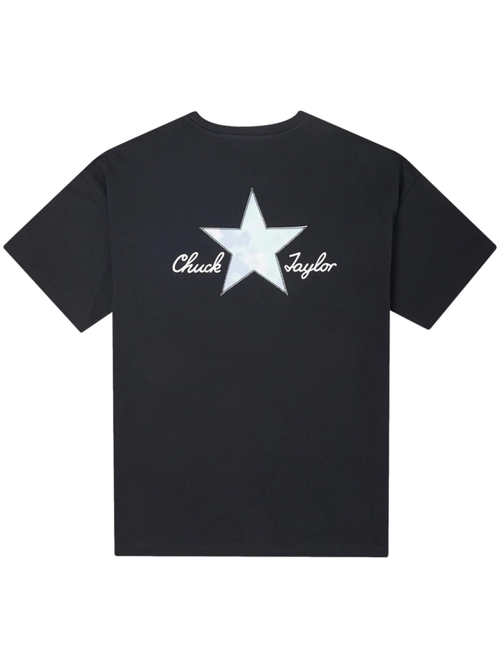 Mujer vistiendo playera negra de manga corta marca Converse con un pequeño logotipo de estrella blanca en el pecho.