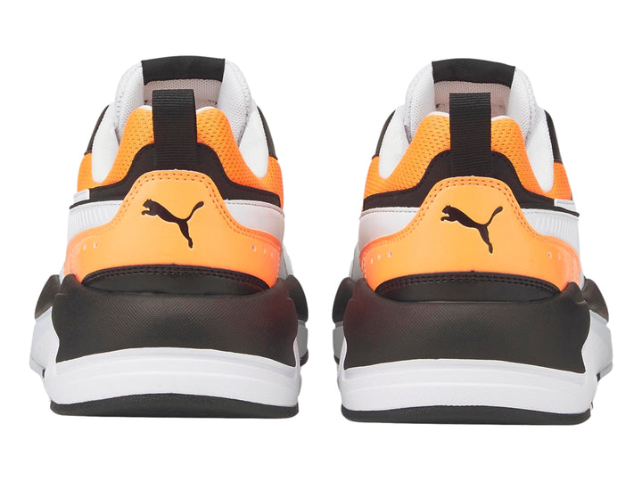 Tenis deportivos PUMA en color blanco con detalles en naranja fluorescente y negro.
