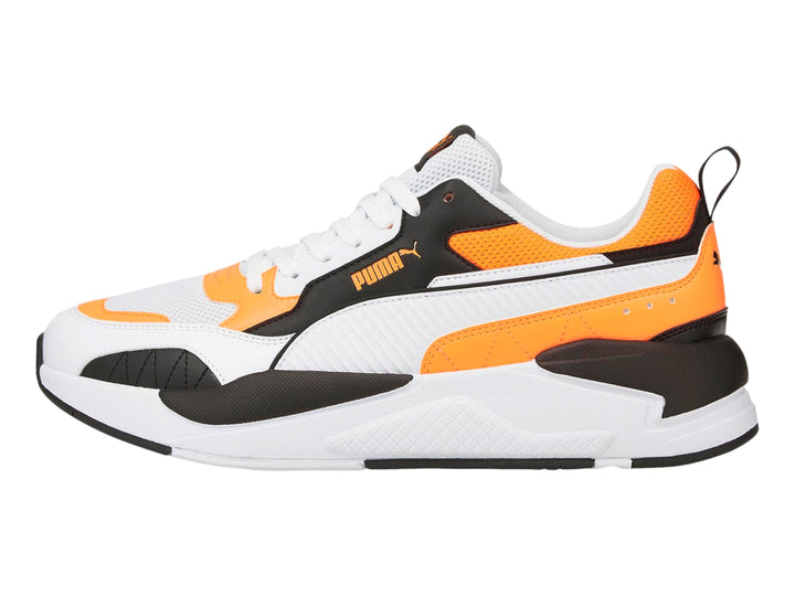 Tenis deportivos PUMA en color blanco con detalles en naranja fluorescente y negro.
