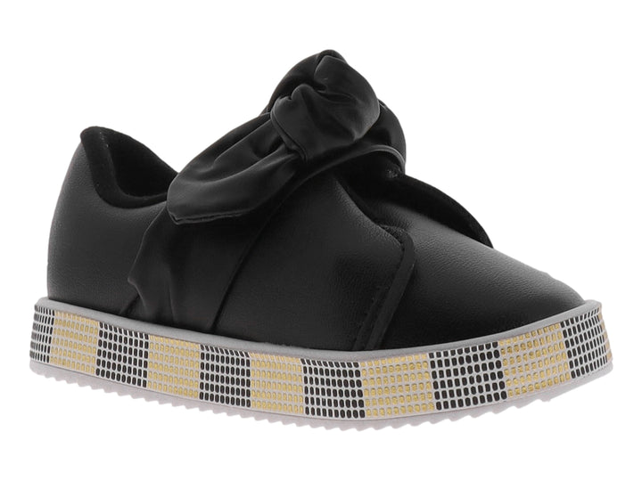 Zapato negro para niña con moño decorativo y suela con patrón de cuadros negros y dorados.