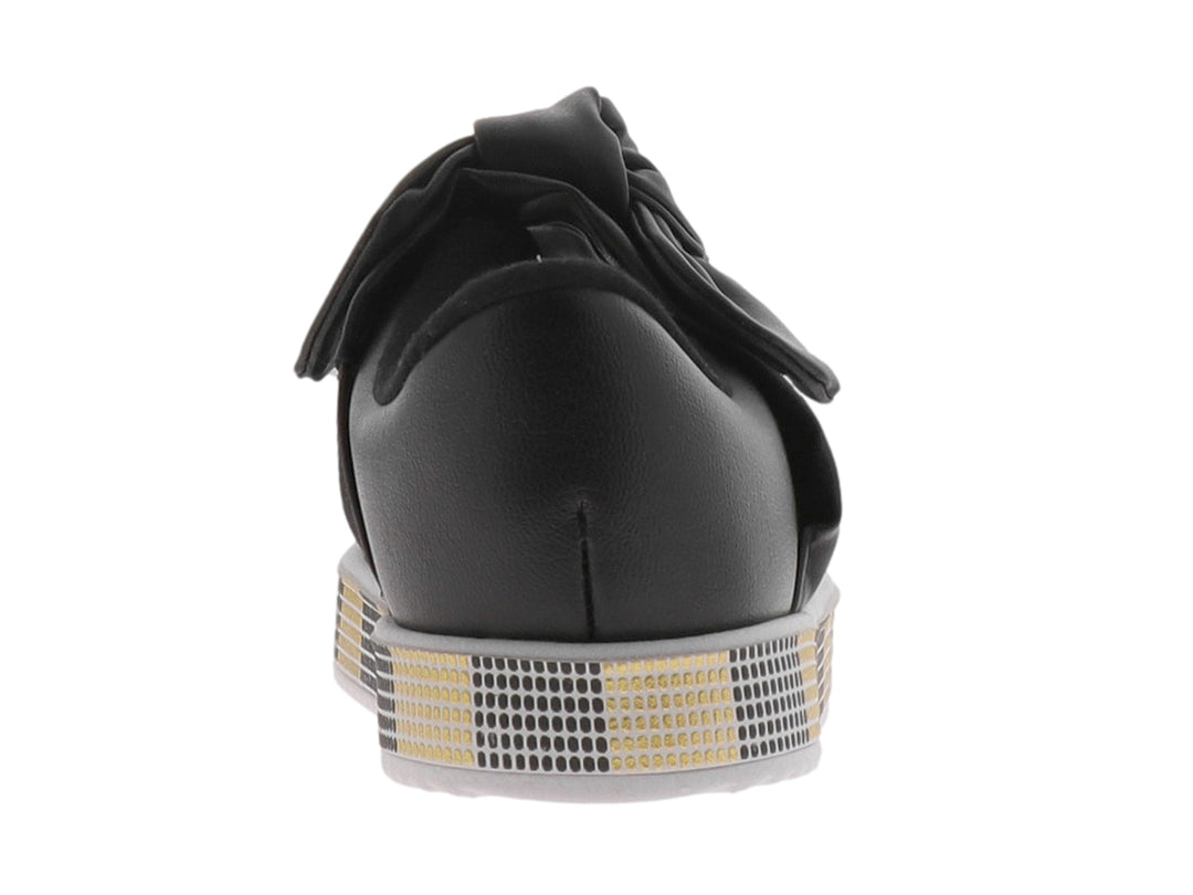 Zapato negro para niña con moño decorativo y suela con patrón de cuadros negros y dorados.