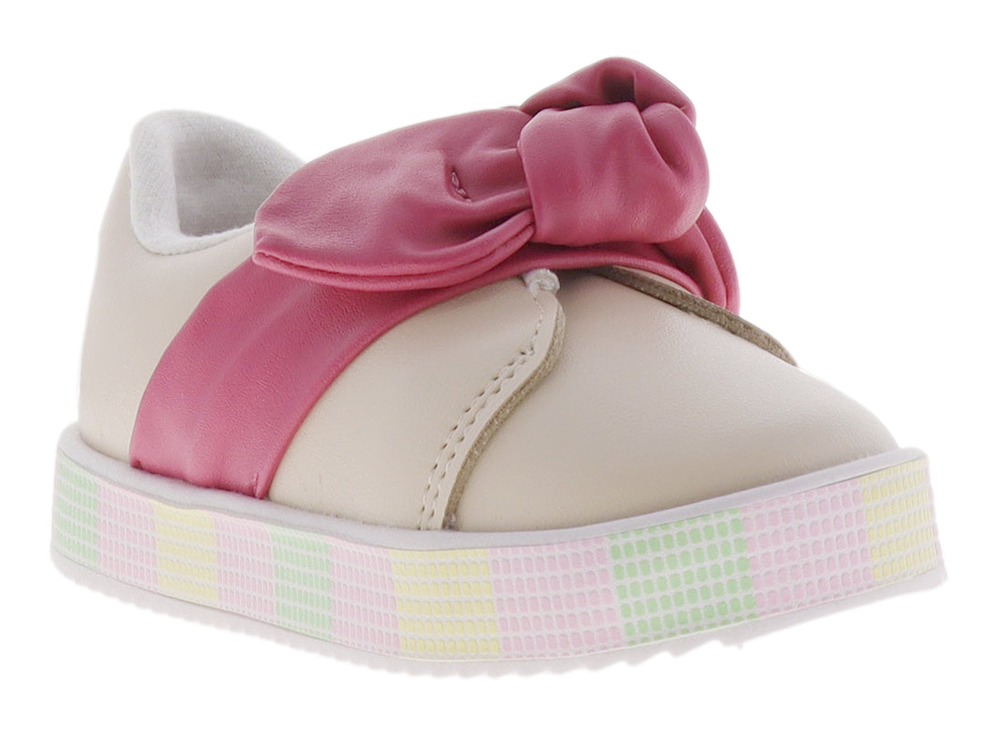 Zapato infantil color crema con un gran moño rosa en la parte superior y suela de plataforma con patrón cuadriculado.