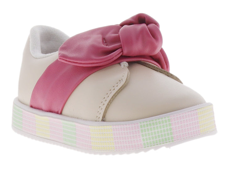 Zapato infantil color crema con un gran moño rosa en la parte superior y suela de plataforma con patrón cuadriculado.