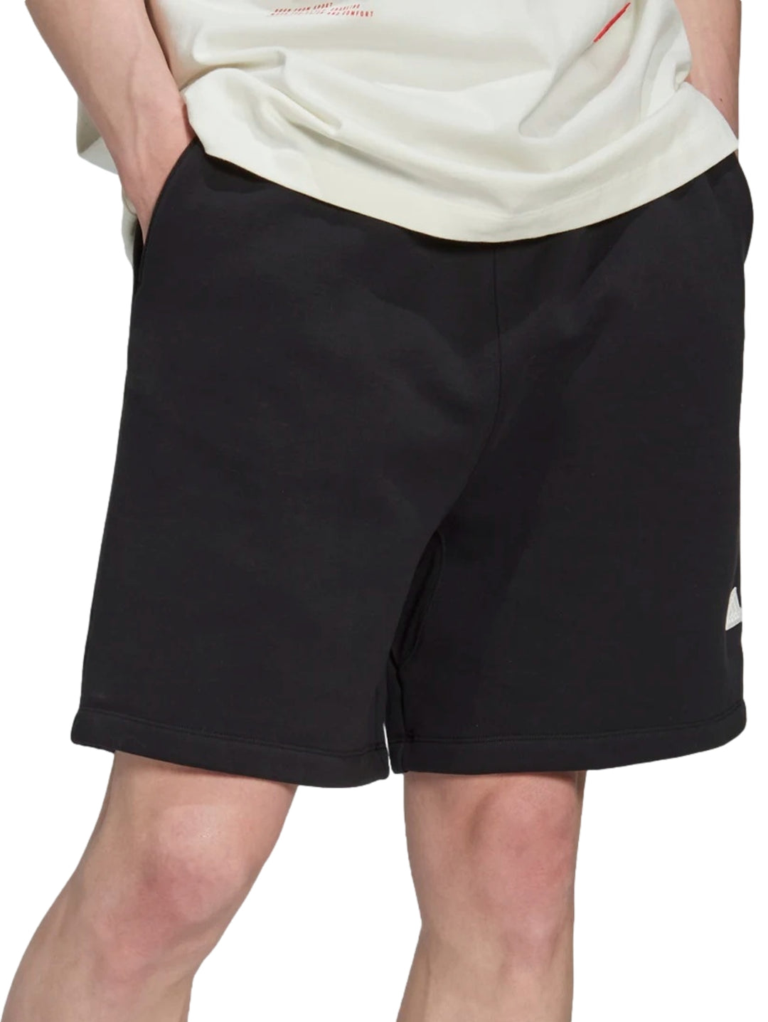 Hombre vistiendo pantalones cortos deportivos Adidas de color negro.