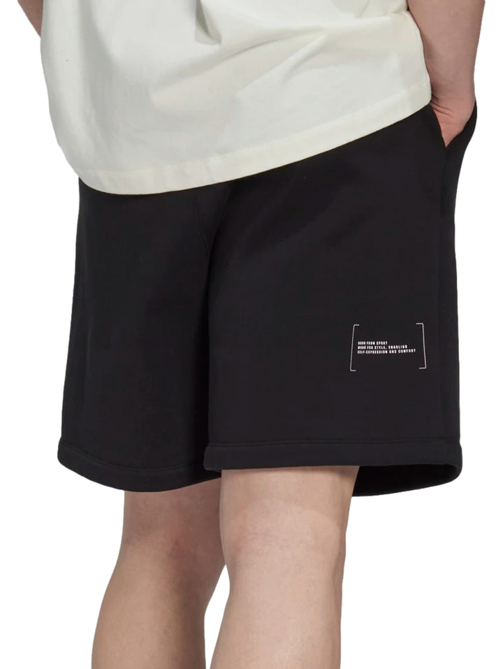 Hombre vistiendo pantalones cortos deportivos Adidas de color negro.