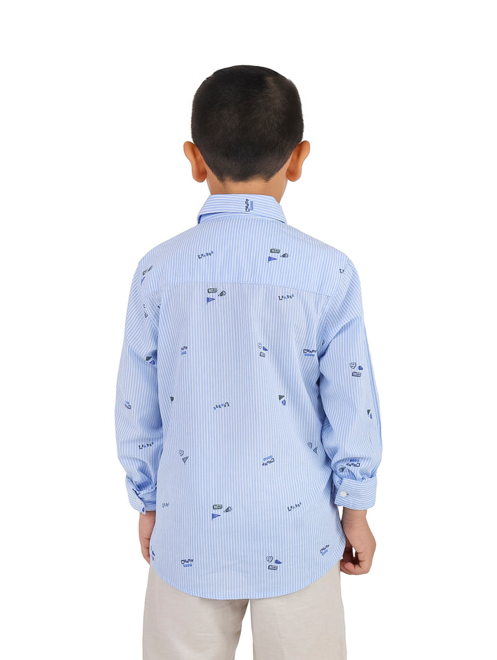 Niño vistiendo una camisa celeste de rayas verticales con pequeños estampados náuticos.