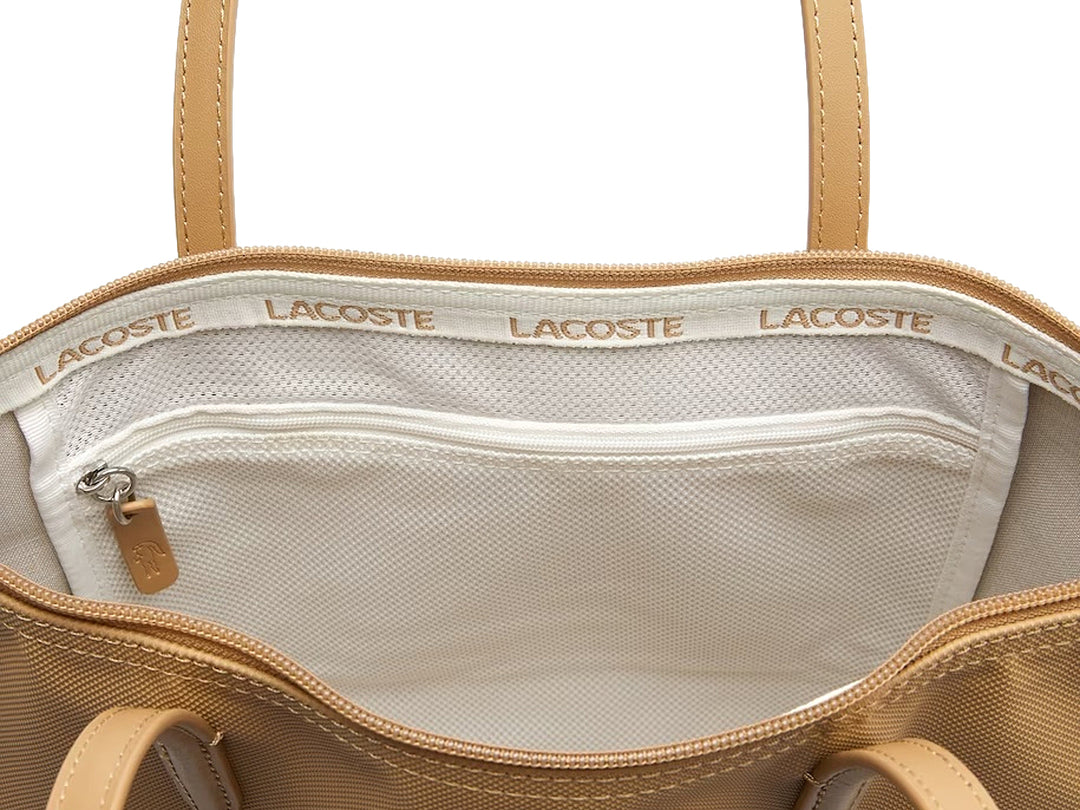 Bolso tote color beige con asas largas y logotipo metálico de Lacoste al frente.