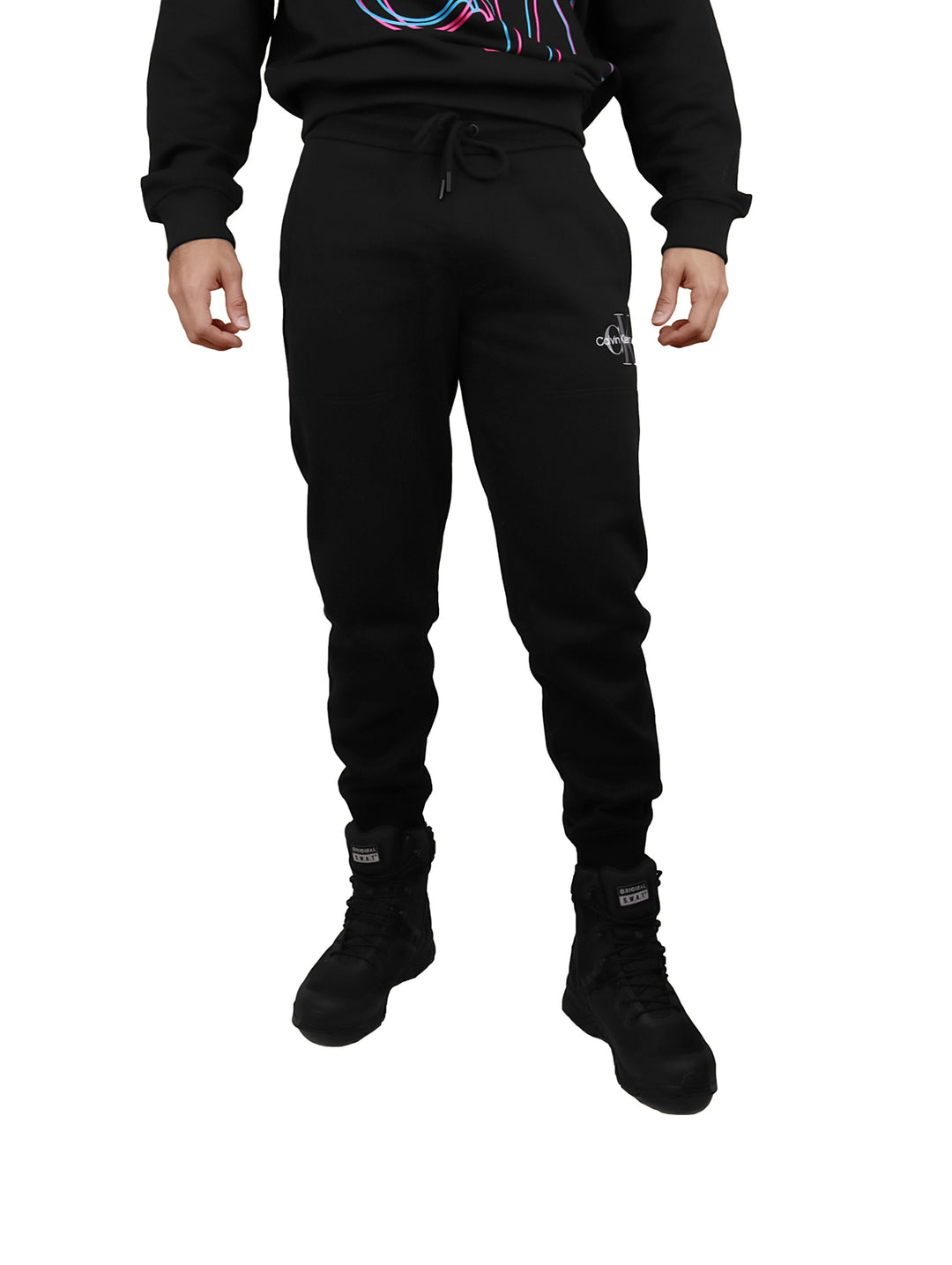 Hombre vistiendo pantalón jogger negro de Calvin Klein con cintura elástica y botas negras.