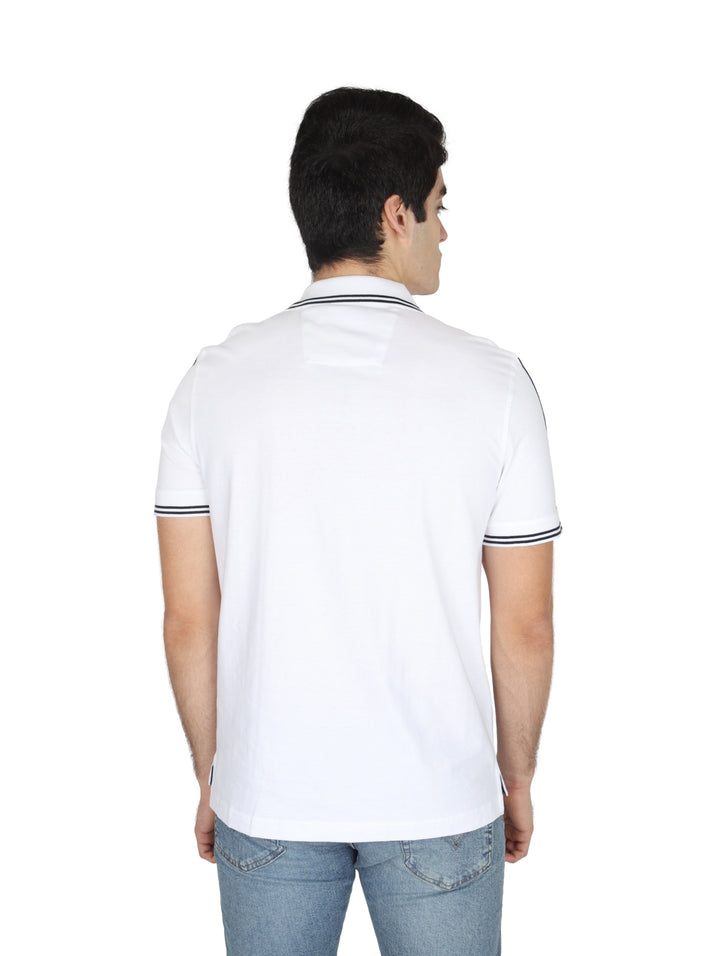 Hombre vistiendo playera polo blanca de marca Nautica con detalles en azul marino en las mangas.