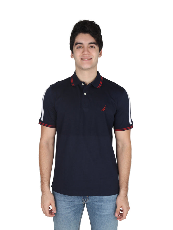 Hombre vistiendo playera polo Nautica color azul marino con detalles en blanco y rojo en mangas y cuello.