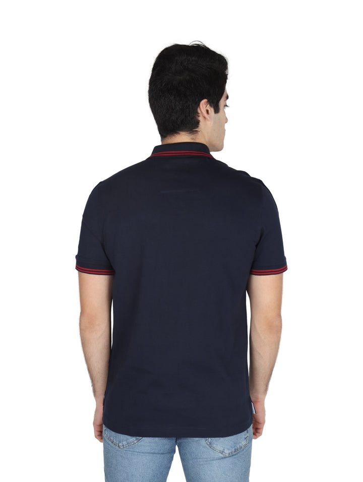 Hombre vistiendo playera polo Nautica color azul marino con detalles en blanco y rojo en mangas y cuello.