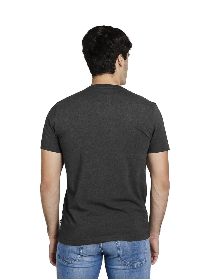 Hombre vistiendo una playera Nautica de manga corta en color gris oscuro con cuello redondo y jeans azules.