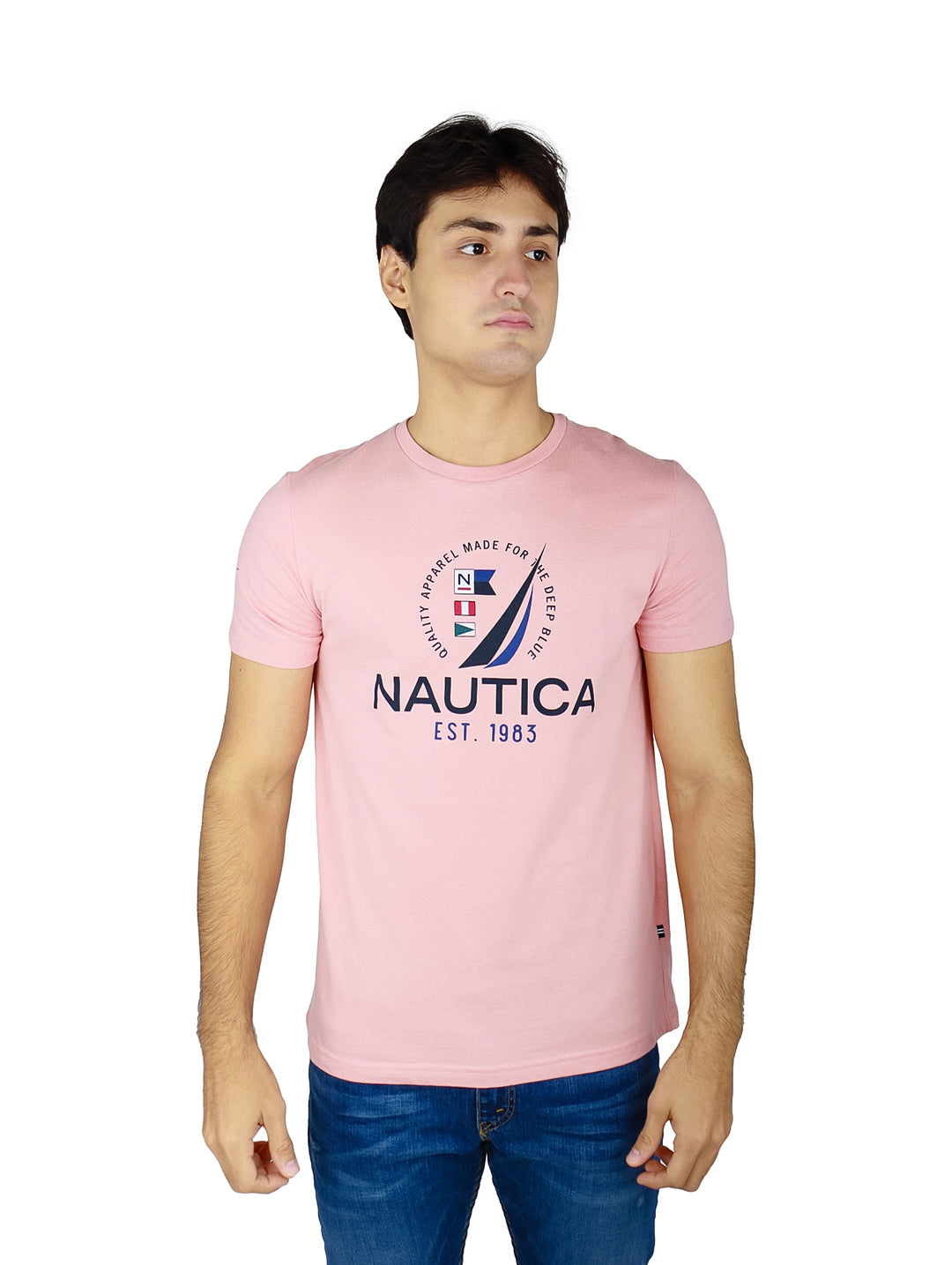 Hombre vistiendo playera Nautica de color rosa con logotipo estampado en el pecho y pantalones mezclilla azules.