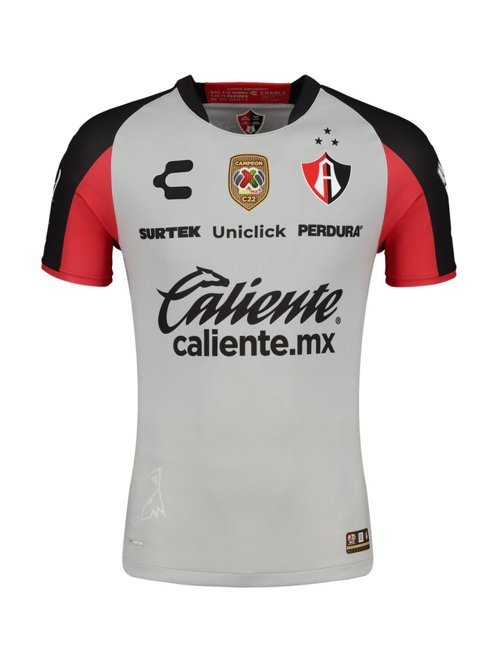 Jersey deportivo Charly color gris con detalles en rojo y negro y logotipos de patrocinadores.