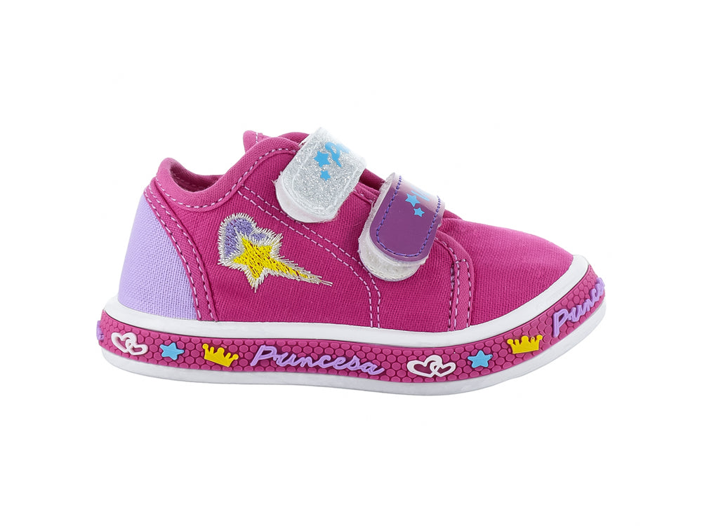 Zapato infantil color fucsia con detalles brillantes, suela blanca y adornos de coronas y estrellas.