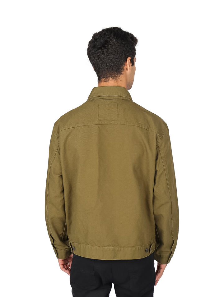 Hombre vistiendo una chaqueta trucker de color verde oliva oscuro.