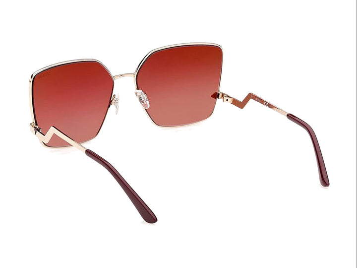Lentes de sol GUESS para mujer con armazón dorado y cristales cuadrados en color guinda degradado.