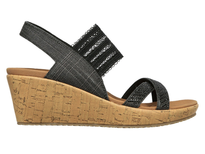 Sandalia de cuña Skechers con tiras negras de tela y plataforma de corcho color beige.