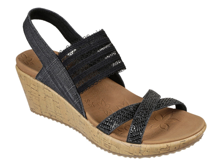 Sandalia de cuña Skechers con tiras negras de tela y plataforma de corcho color beige.