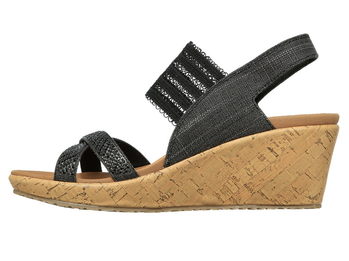 Sandalia de cuña Skechers con tiras negras de tela y plataforma de corcho color beige.