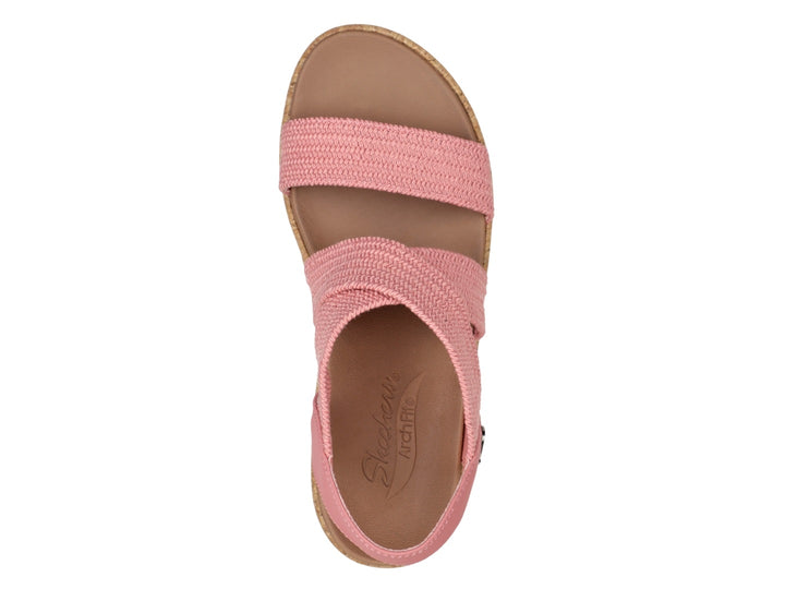 Sandalia Skechers de plataforma en color rosa con tiras tejidas y suela de corcho beige para mujer.