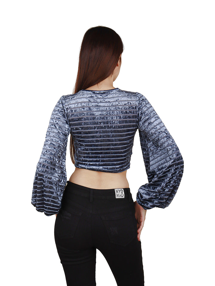 Blusa corta color azul de tela brillante con mangas largas y detalle de jareta frontal.