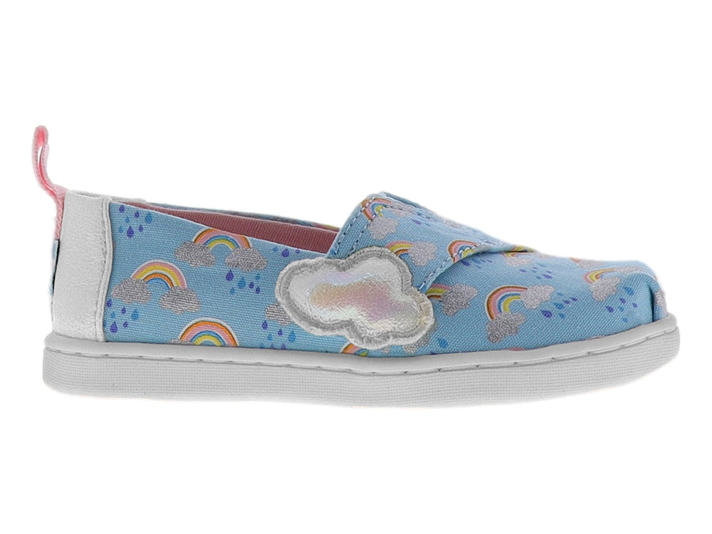 Zapato slip-on azul para niña con estampado de arcoíris, detalle de nube blanca y talón rosa.