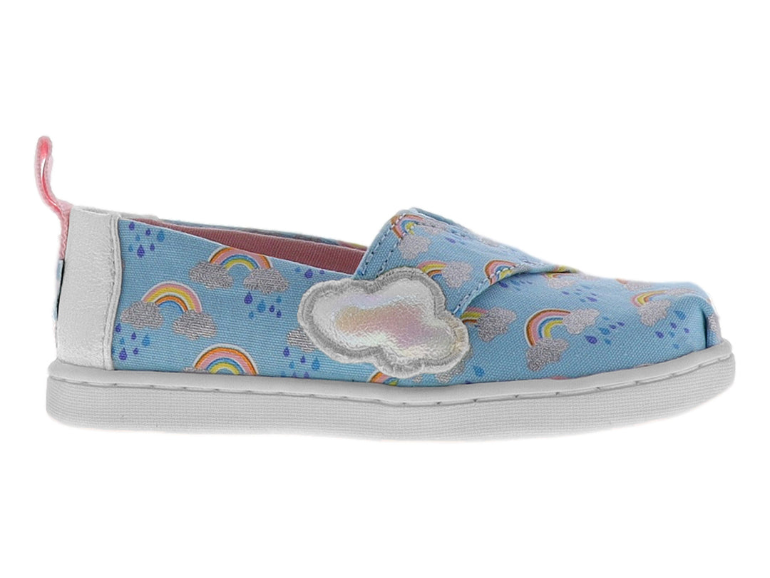 Zapato slip-on azul para niña con estampado de arcoíris, detalle de nube blanca y talón rosa.