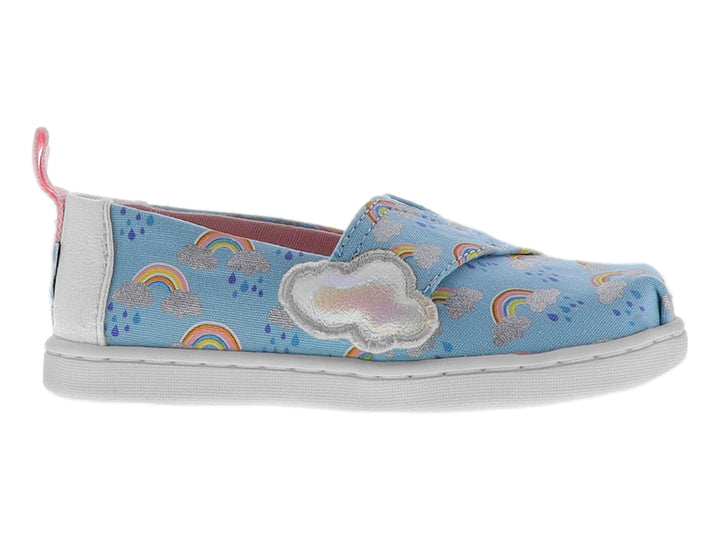Zapato slip-on azul para niña con estampado de arcoíris, detalle de nube blanca y talón rosa.