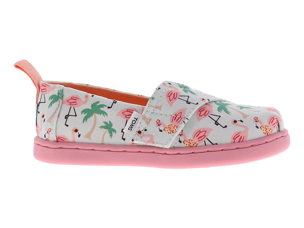 Zapato TOMS infantil azul claro con estampado de flamencos rosas y palmeras, con suela rosa.