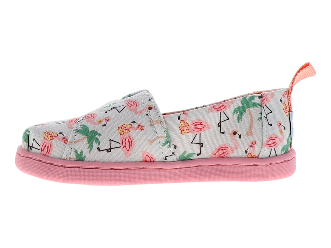 Zapato TOMS infantil azul claro con estampado de flamencos rosas y palmeras, con suela rosa.
