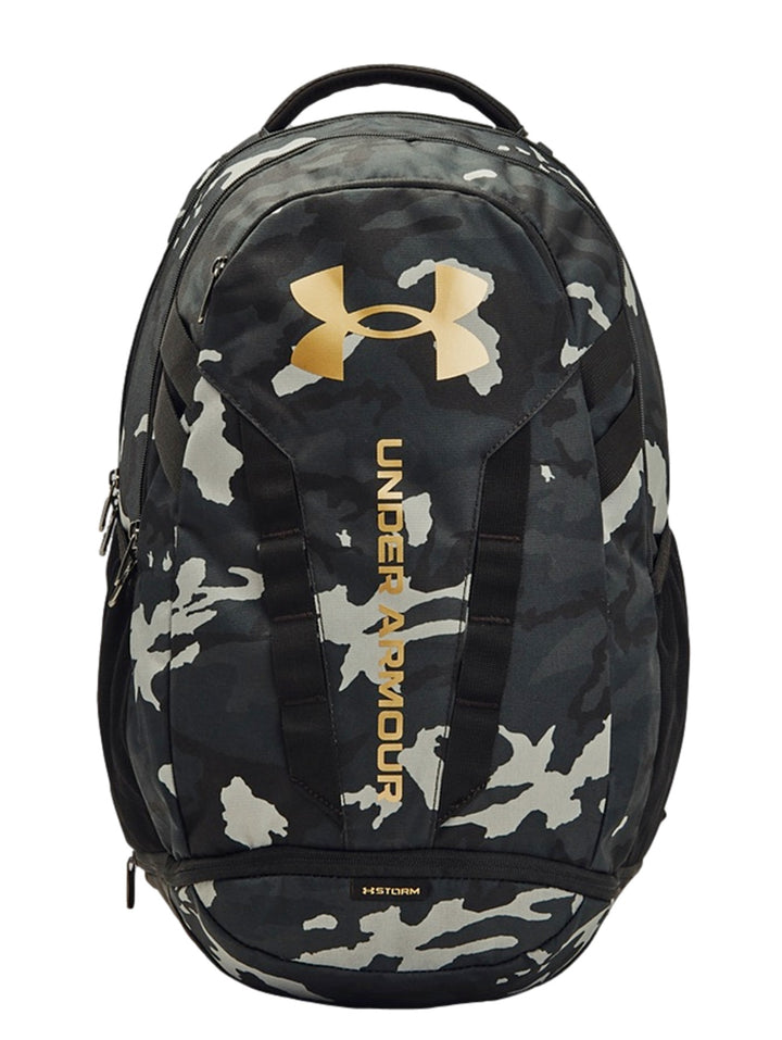 Mochila Under Armour Hustle 5.0 con estampado de camuflaje en tonos negro y gris con logos dorados.