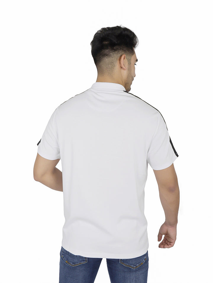 Hombre vistiendo playera polo blanca DKNY con detalles negros en hombros y cuello.