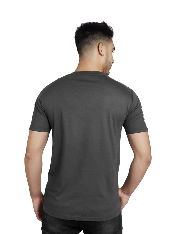 Hombre vistiendo playera gris oxford de manga corta con estampado de calavera y bandana en el pecho.