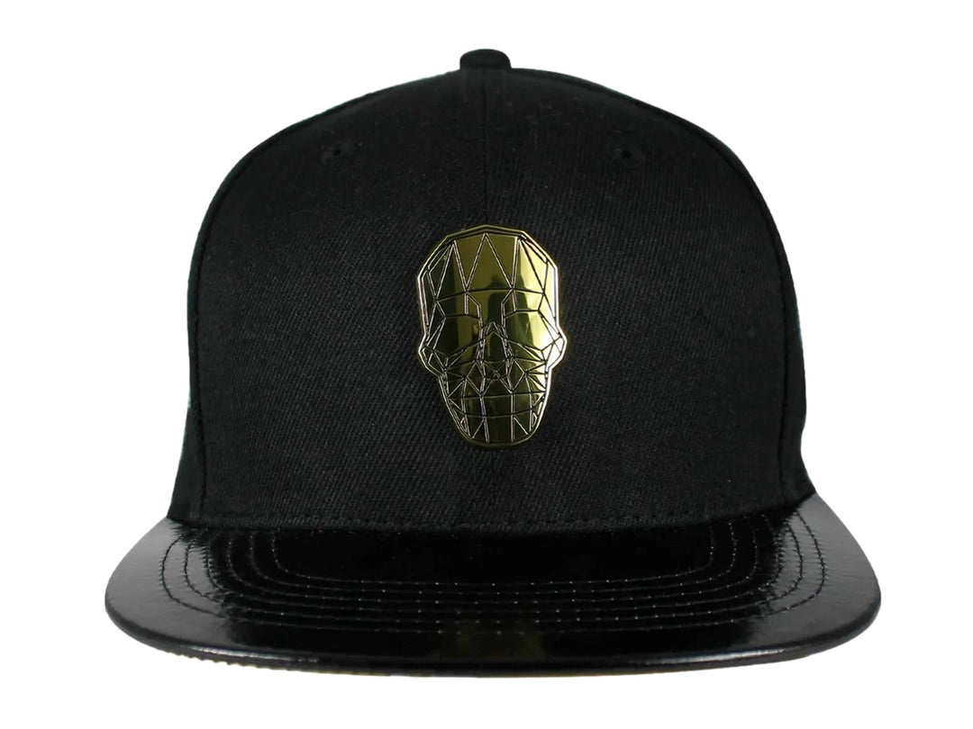 Gorra snapback color negro con visera plana y un emblema dorado en forma de calavera geométrica al frente.