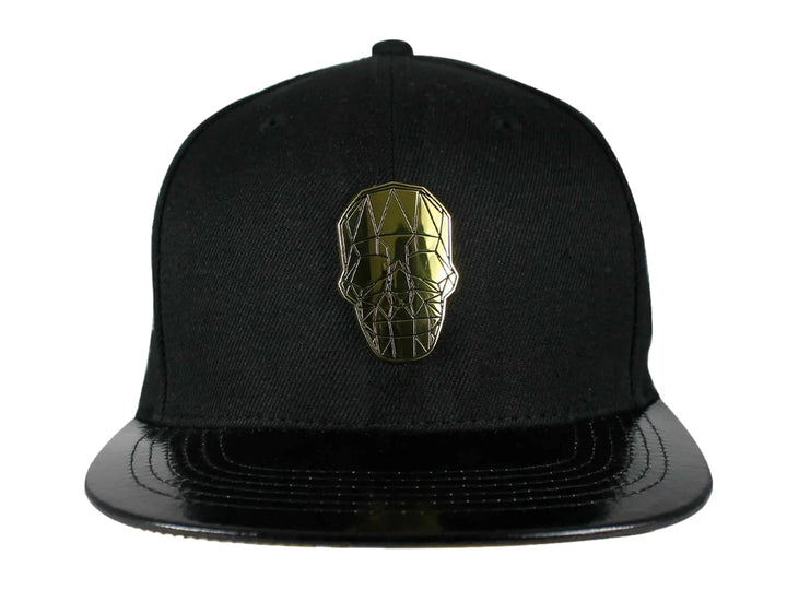 Gorra snapback color negro con visera plana y un emblema dorado en forma de calavera geométrica al frente.