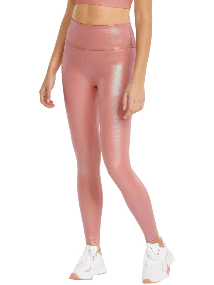Mujer vistiendo leggings PUMA de color rosa iridiscente con talle alto y tenis blancos.