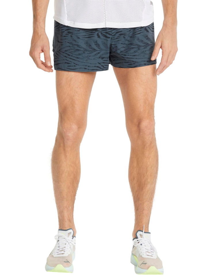 Hombre vistiendo shorts deportivos PUMA color gris oscuro con corte split para running.