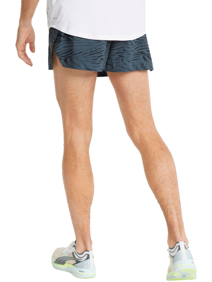 Hombre vistiendo shorts deportivos PUMA color gris oscuro con corte split para running.