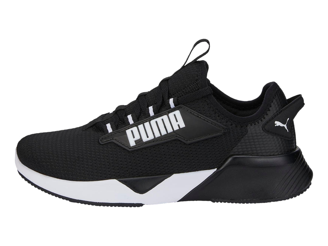 Tenis deportivos PUMA para niños en color negro con suela blanca y logotipo lateral blanco.