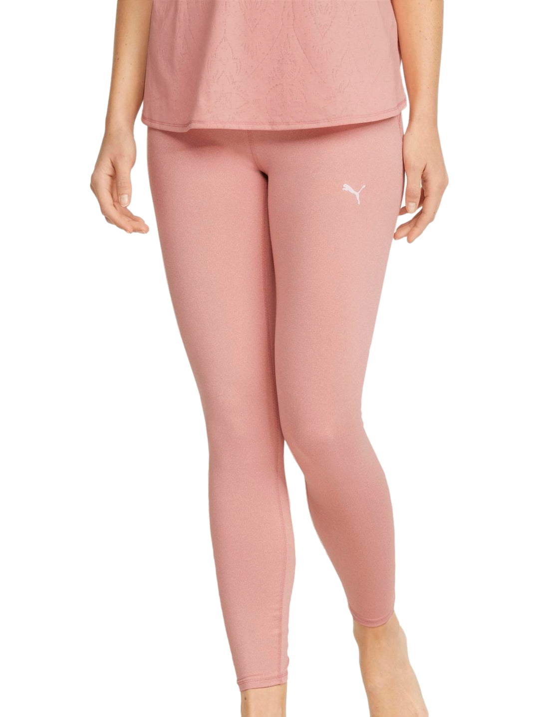 Mujer vistiendo leggings deportivos PUMA de color rosa palo, corte 7/8 y ajuste ceñido.