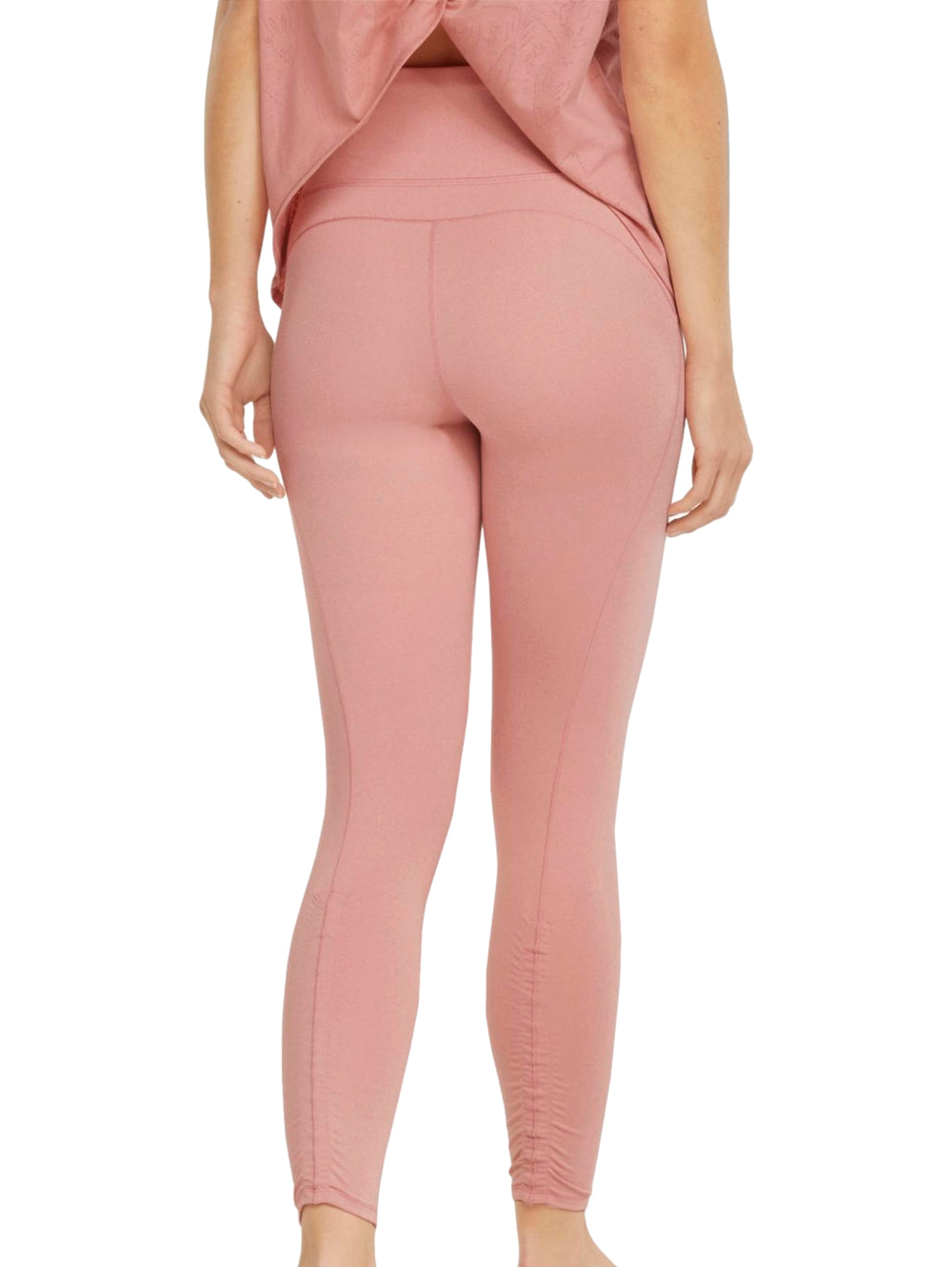 Mujer vistiendo leggings deportivos PUMA de color rosa palo, corte 7/8 y ajuste ceñido.