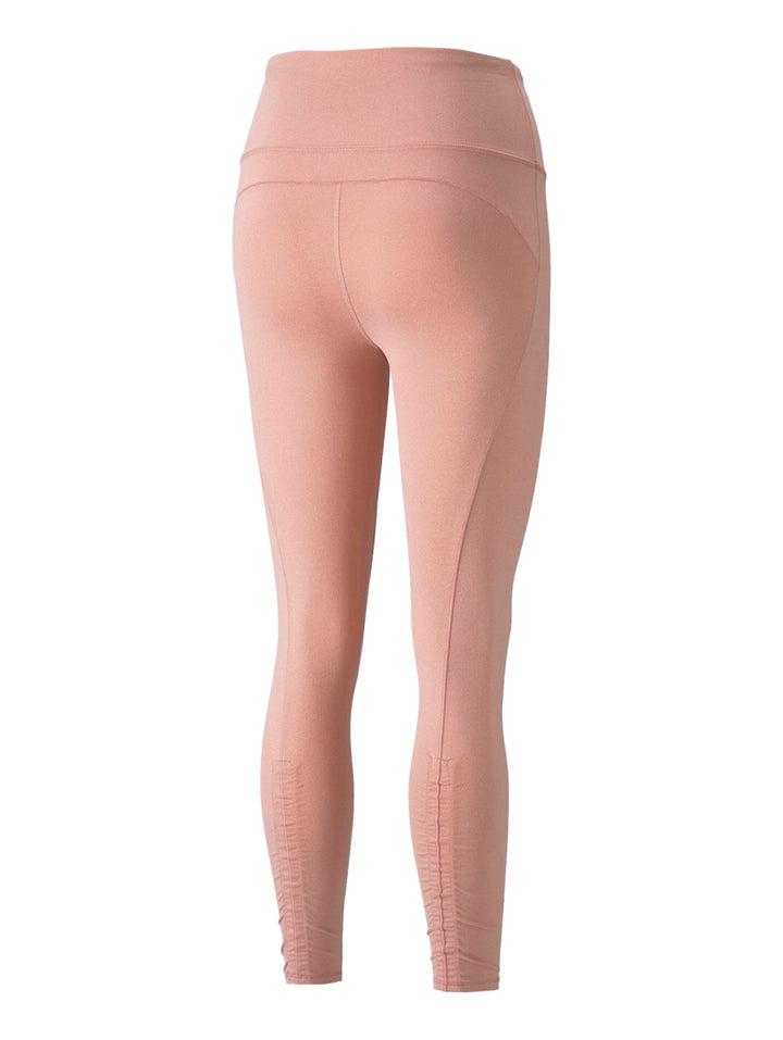 Mujer vistiendo leggings deportivos PUMA de color rosa palo, corte 7/8 y ajuste ceñido.