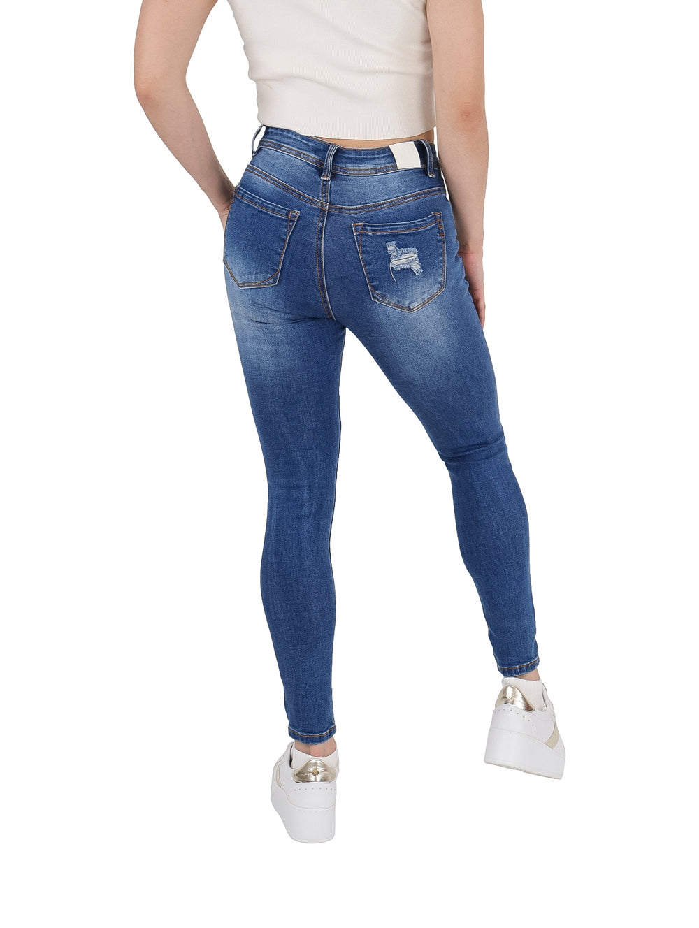 Mujer vistiendo pantalones jeans ajustados color azul con efectos de destrucción y roturas.