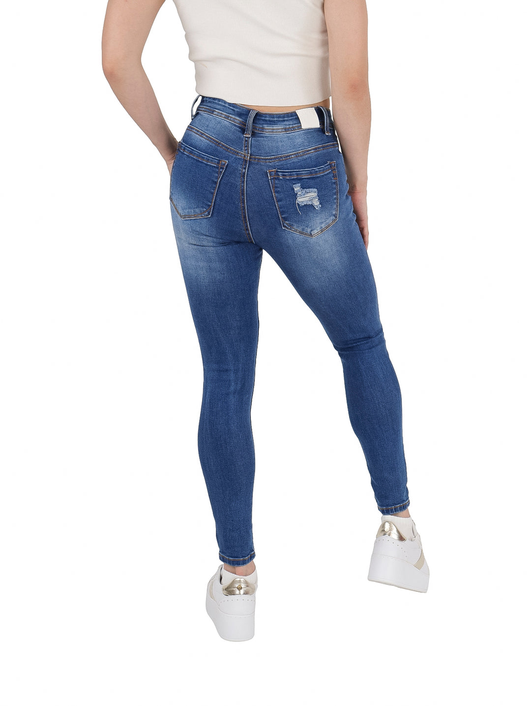 Mujer vistiendo pantalones jeans ajustados color azul con efectos de destrucción y roturas.
