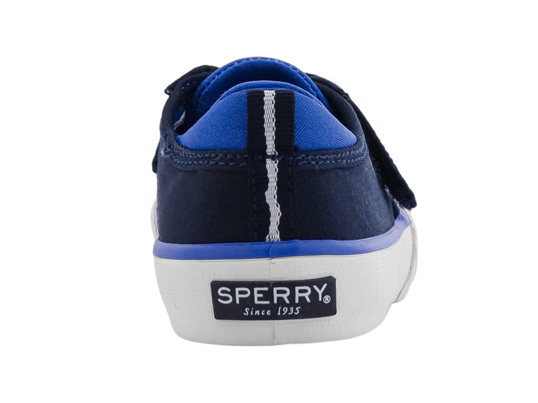 Zapato infantil Sperry color azul marino con suela blanca, cierre de velcro y agujetas decorativas.