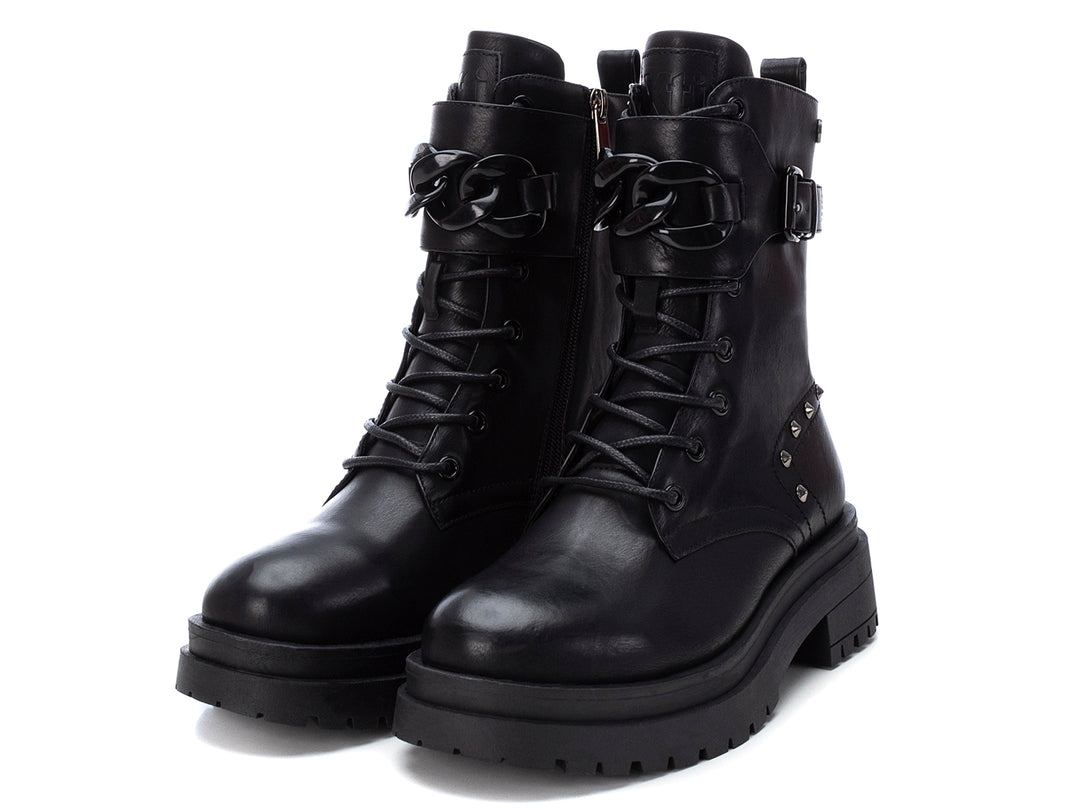 Bota negra de caña media con suela track, agujetas, hebilla lateral y detalles de estoperoles plateados.