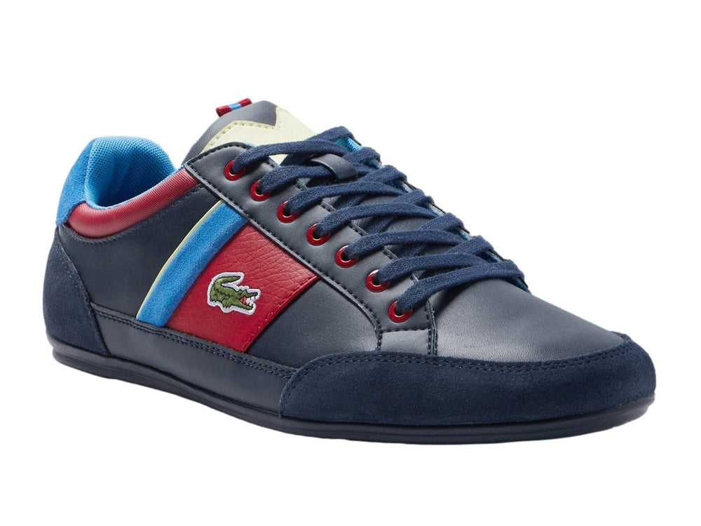 Tenis Lacoste azul marino con franjas laterales en rojo, azul y amarillo y logotipo del cocodrilo.