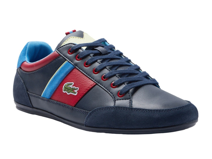 Tenis Lacoste azul marino con franjas laterales en rojo, azul y amarillo y logotipo del cocodrilo.