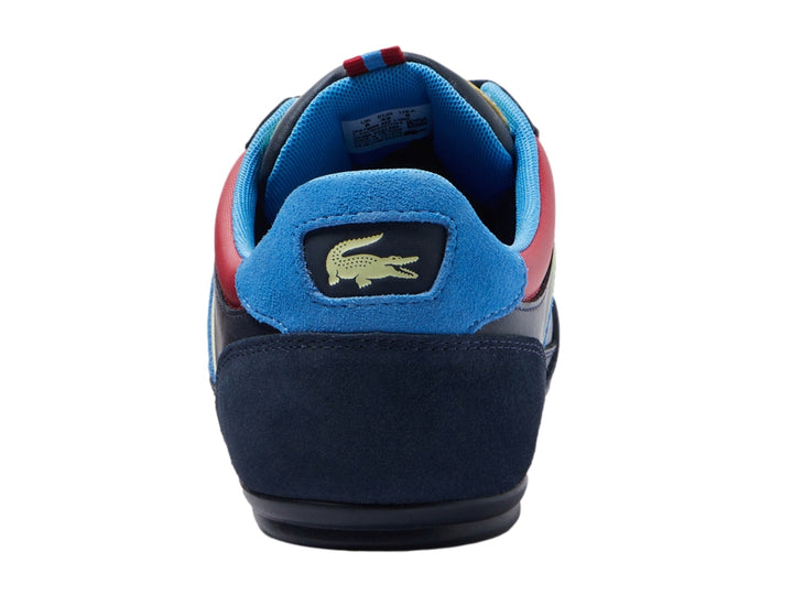 Tenis Lacoste azul marino con franjas laterales en rojo, azul y amarillo y logotipo del cocodrilo.
